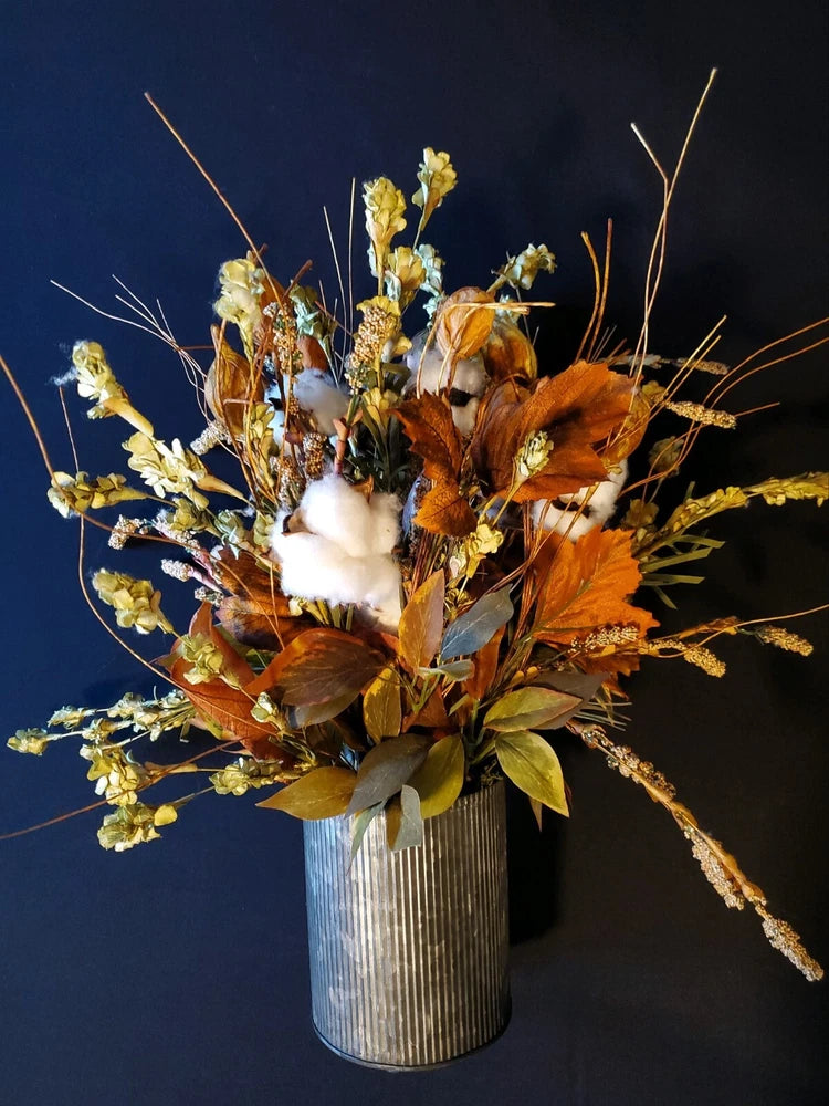 Dried flower arrangement in ribbed galvanized metal vase with orange and yellow blooms