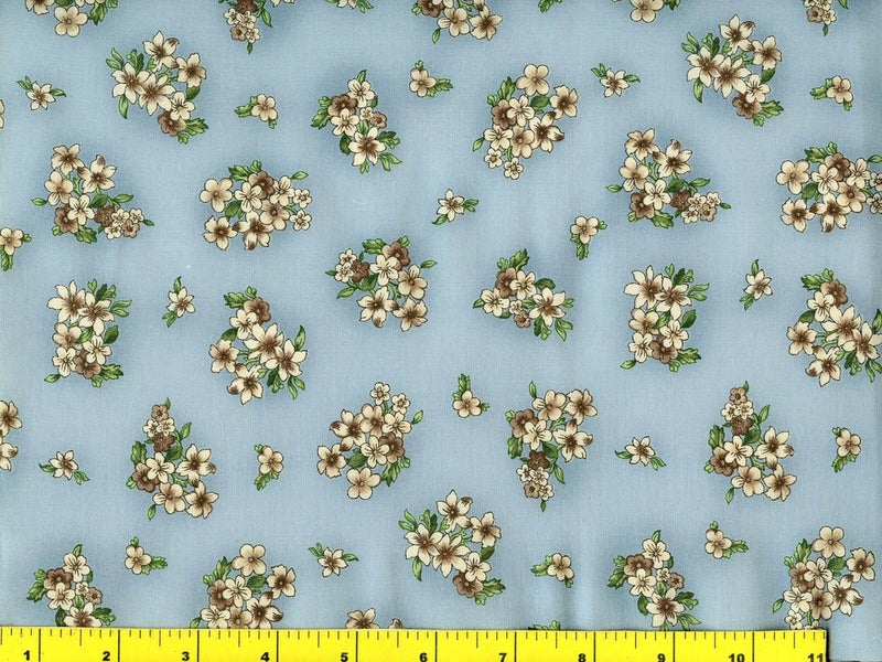 Light blue quilting fabric with scattered small white flower bouquets and green leaves
