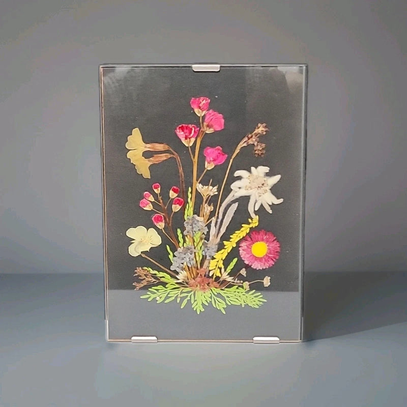Rimless frame wall art with pressed flowers, pink blooms and yellow daisies on dark backing