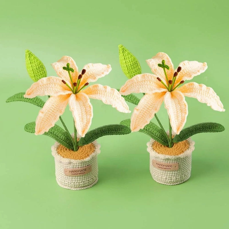 Pair of artificial knitted lily flowers in cream pots with green leaves and buds