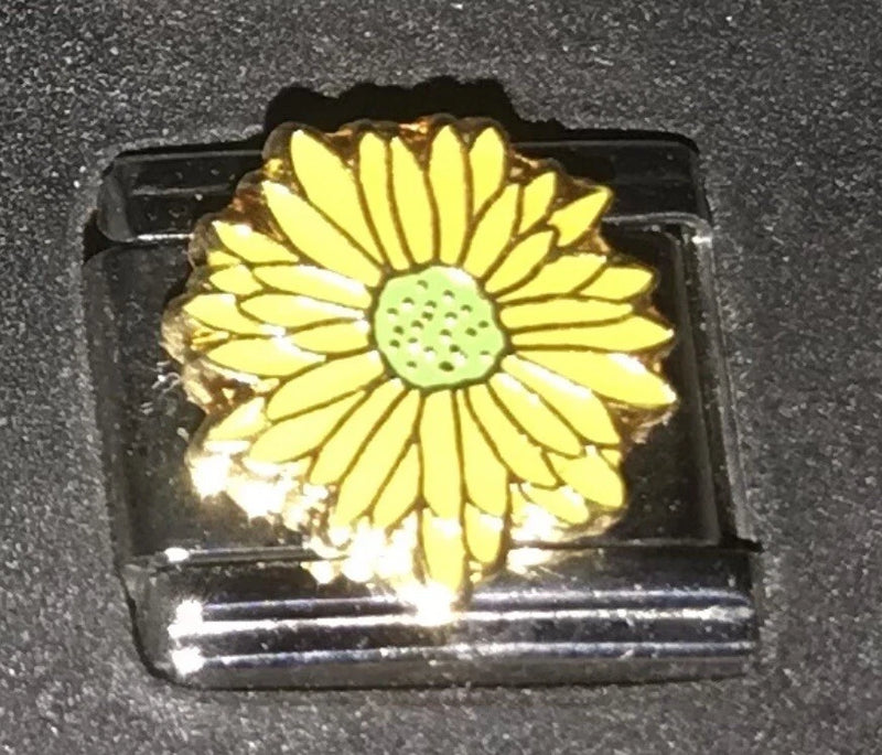 Sunflower enamel charm with yellow petals and green center on a dark backing