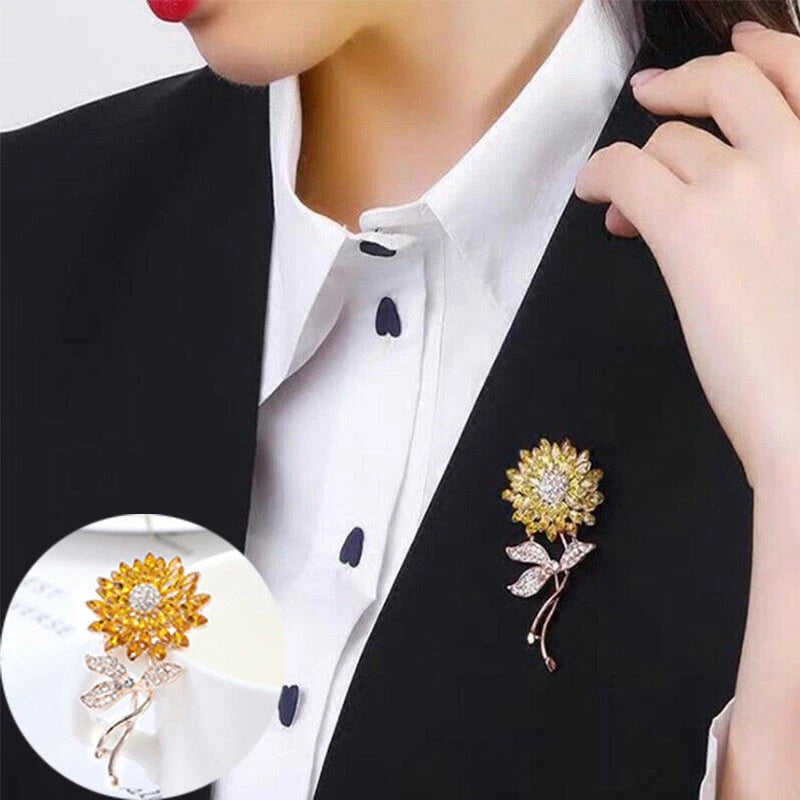 Gold-tone sunflower rhinestone brooch pin with two leaves, worn on a dark lapel