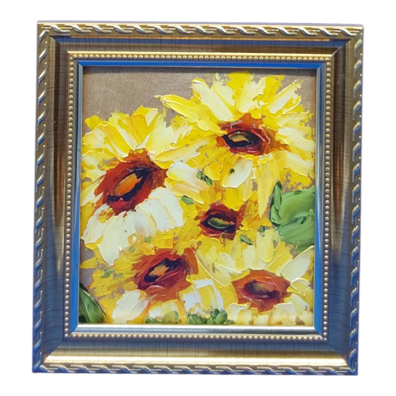 Framed sunflower wall art with yellow blooms, red centers, and green leaves in ornate gold frame