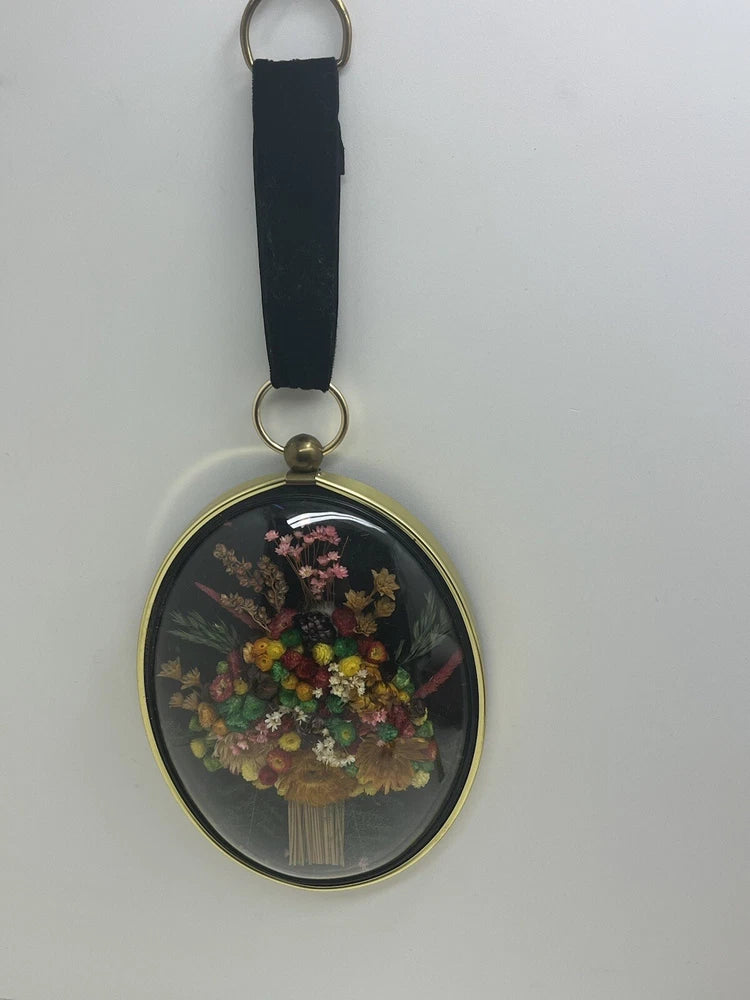 Oval glass dome wall hanging with dried flowers and black hanging strap