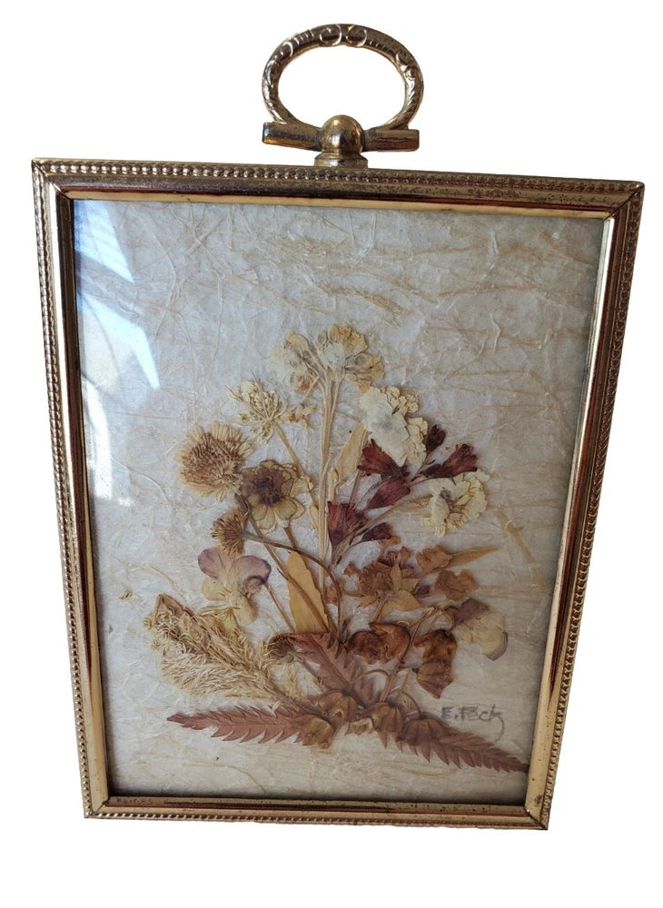 Vintage framed dried flower wall art with bronze tone trim and slightly curved glass