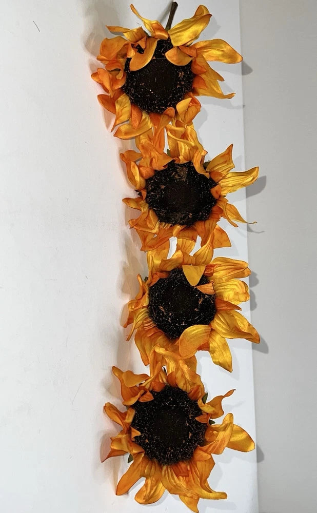 Artificial sunflower stems set with four yellow-orange blooms and dark centers, with leaves