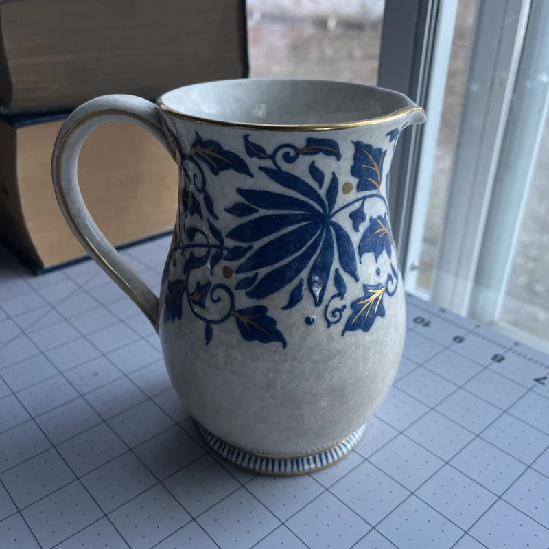 Blue and gold floral pitcher with vine pattern, curved handle and spout
