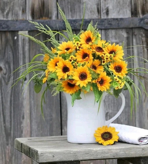 Artificial sunflower bouquet in white vase with green leaves and slender stems