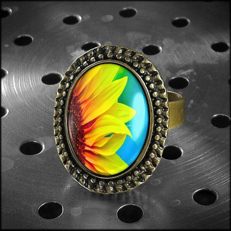 Antique-style oval glass sunflower ring, yellow petals on blue cabochon