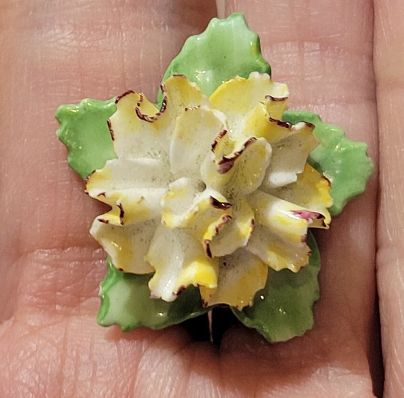 Flower-shaped bone china brooch pin with yellow and cream petals, green leaf accents