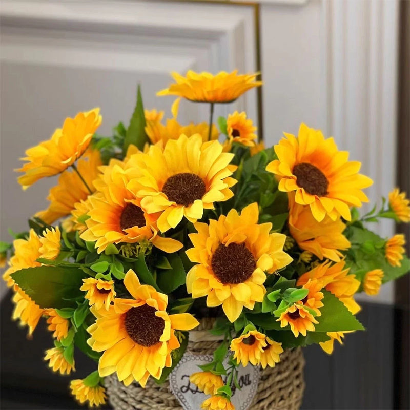 Artificial sunflower bouquet with yellow blooms, dark centers, and green leaves in a wicker basket