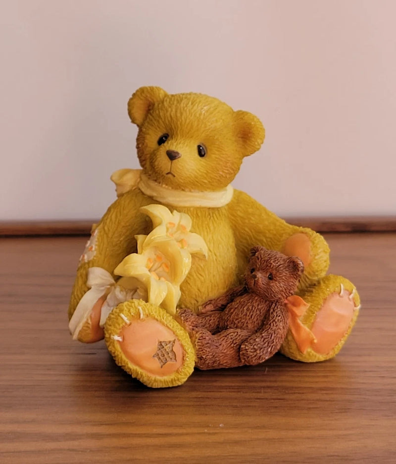 Stuffed teddy bear figurine holding a lily and a small brown bear