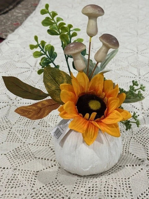 Orange sunflower floral arrangement with green leaves in a white mushroom pot