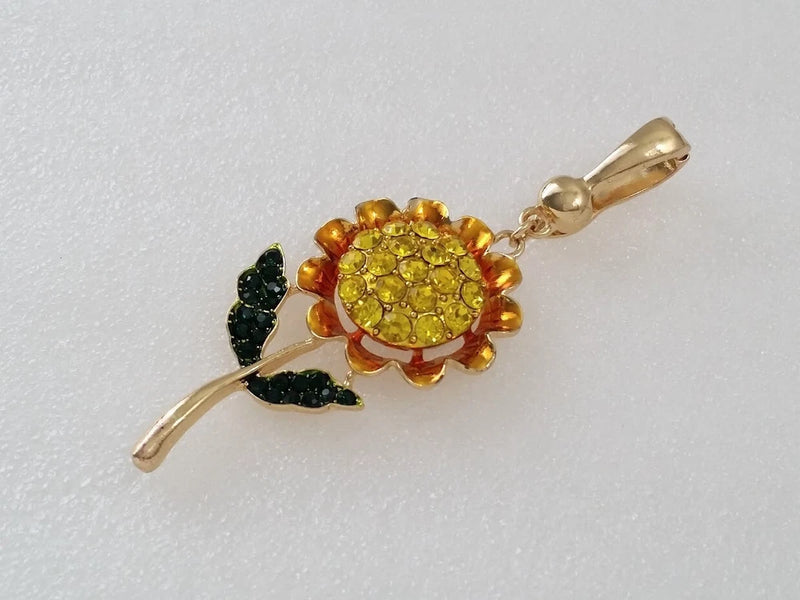 Gold-tone sunflower pendant with yellow and amber crystals, green crystal leaves, bail clasp