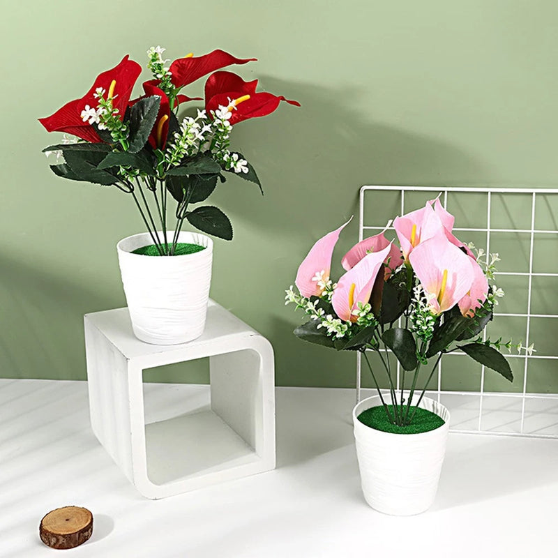Small potted faux calla lily flower arrangement with pink blooms, green leaves, white pot