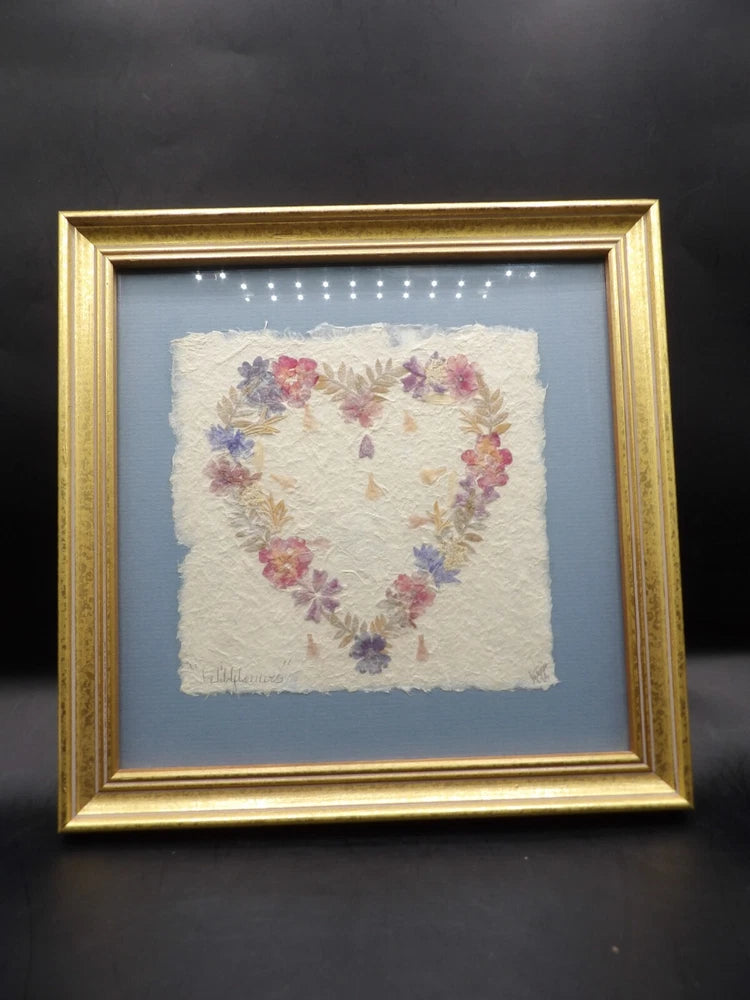 Framed pressed flower heart artwork with colorful dried flowers in a gold border