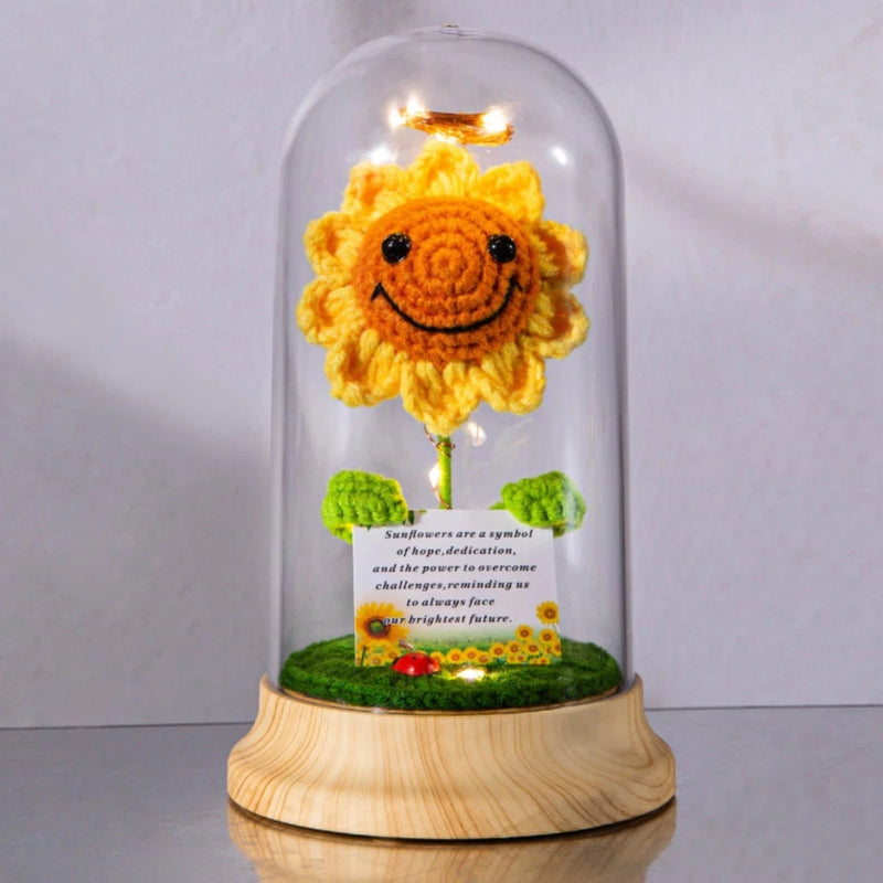 Crochet sunflower figurine under clear plastic dome with wooden base and green grass mat