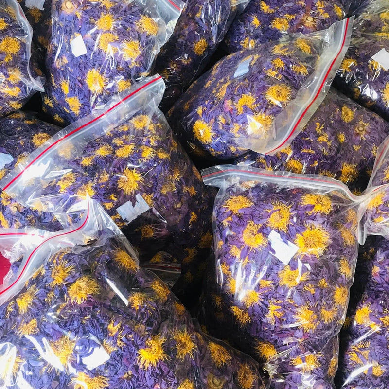 Dried blue lotus flower buds in clear sealed plastic bags with purple petals and yellow centers