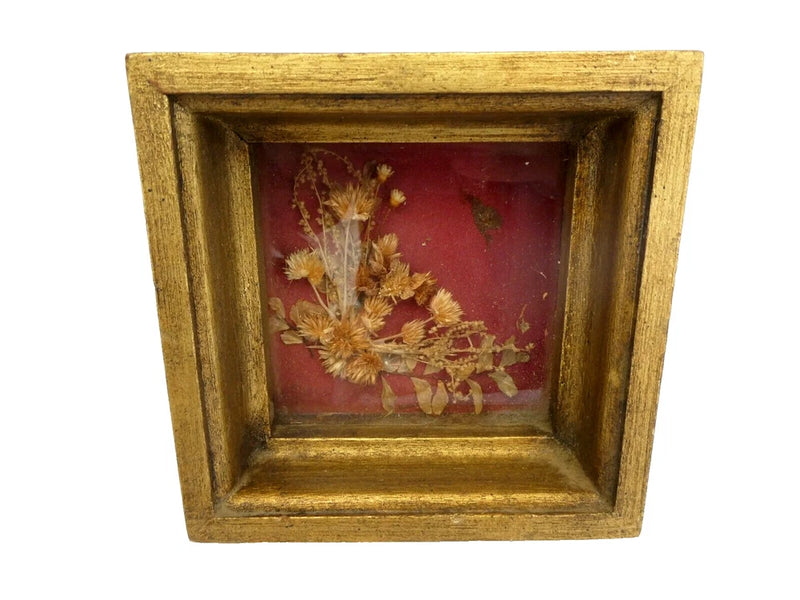 Gold shadow box with dried bouquet arrangement on red backing