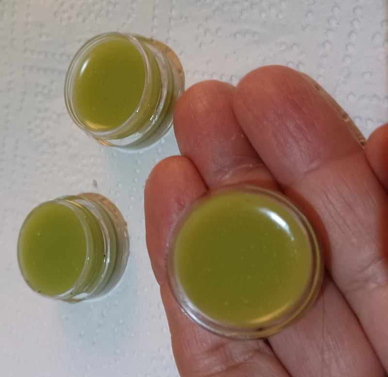 Small clear jar of green growth paste held in hand