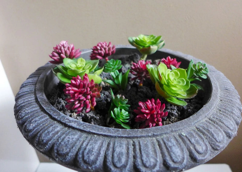 Artificial succulent plant set in round gray planter bowl with green and pink blooms