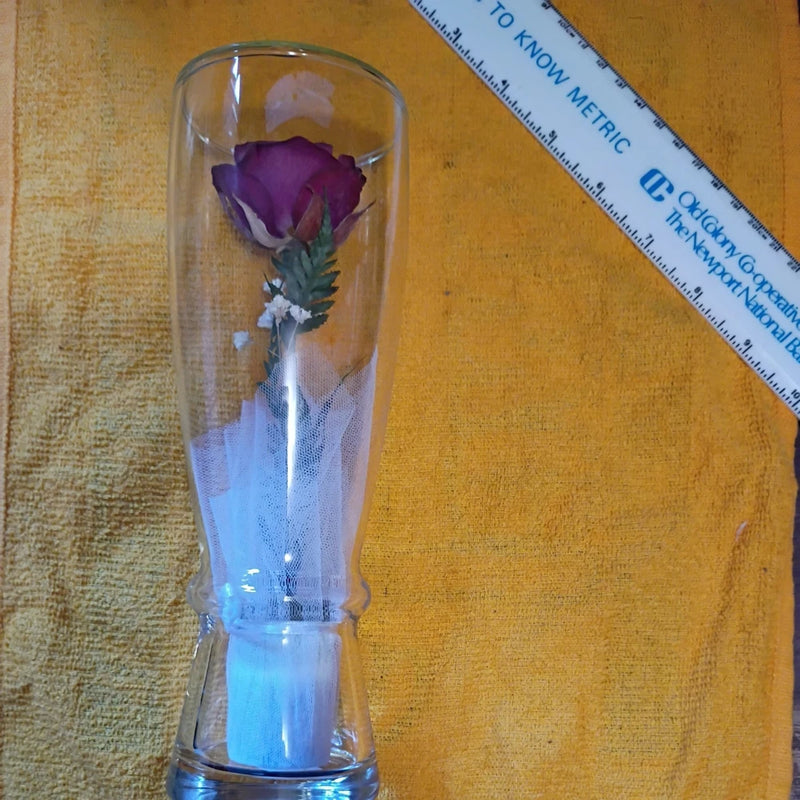 Sealed glass rose preserved in clear cylinder vase with purple flower and dried greenery