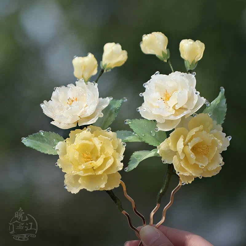 Yellow peony flower hair pins with green leaves, held in hand