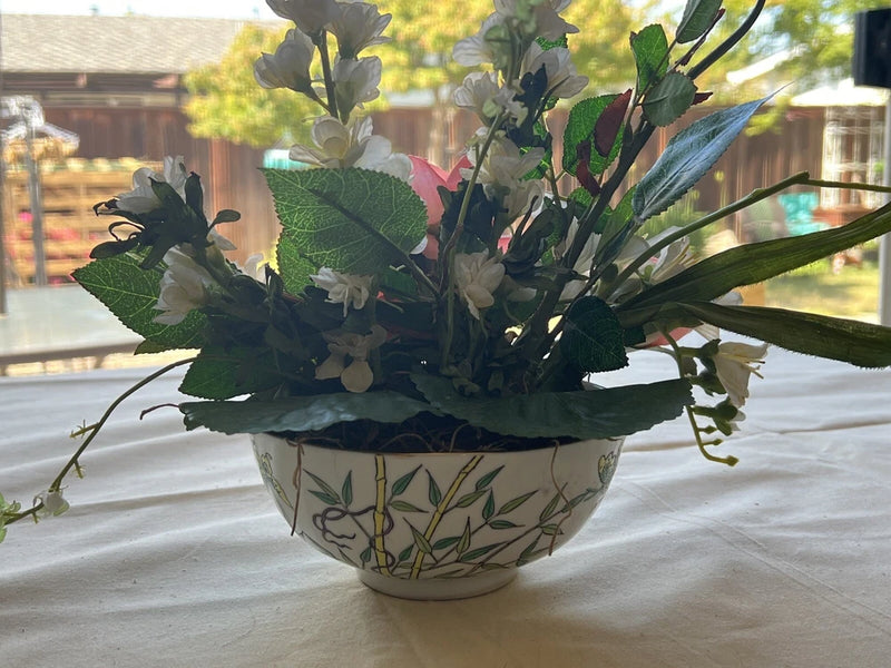 Ceramic decorative bowl with artificial dried flowers and green foliage arrangement