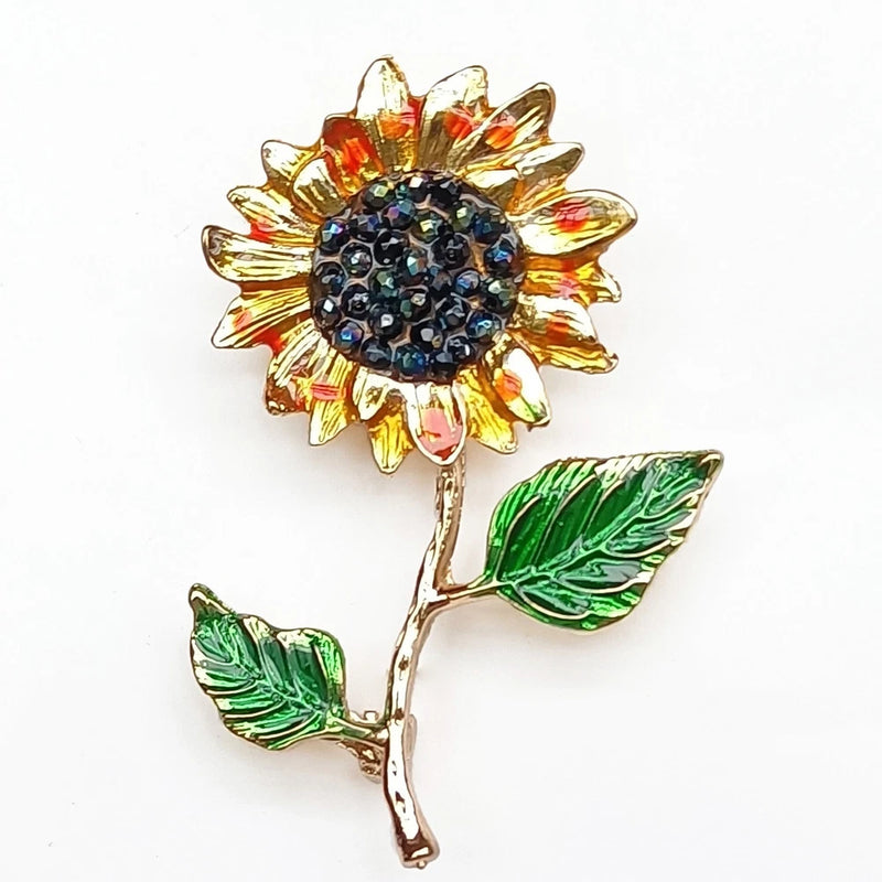 Sunflower brooch pin with orange gold petals, green leaves, and blue rhinestone center