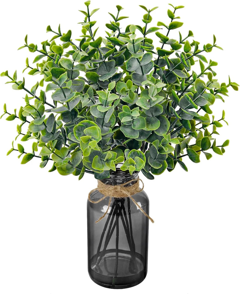 Artificial eucalyptus stems with mixed green leaves in a dark glass vase