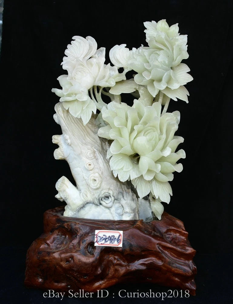 Carved peony flower sculpture with clustered pale blossoms on light branch, on dark wooden stand