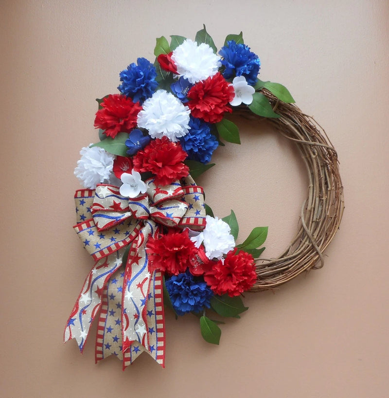 Patriotic grapevine wreath with red, white and blue carnation-style flowers and ribbon