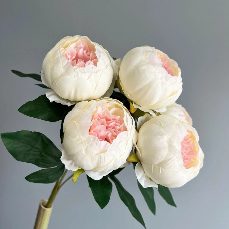 Artificial peony flower bouquet with cream white blooms, pink centers, and green leaves
