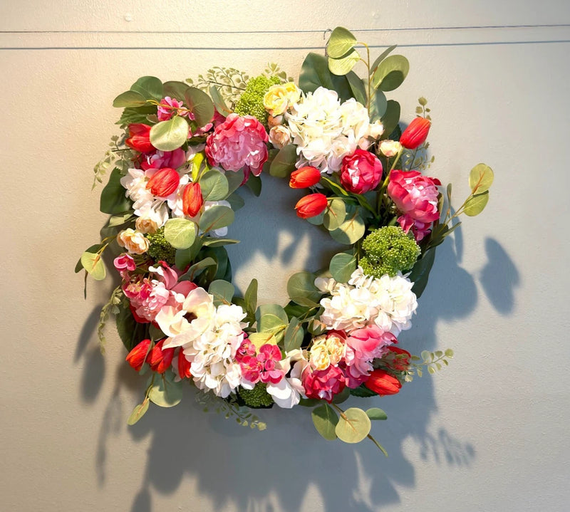 Spring flower wreath with pink and red tulips, white blooms, and green leaves