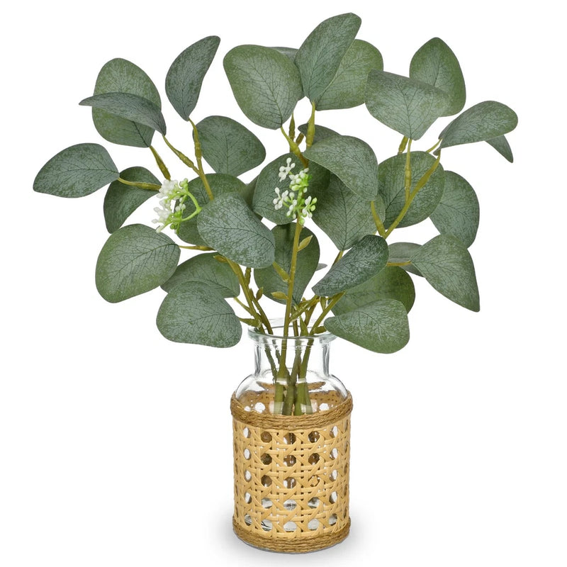 Artificial eucalyptus stems with green leaves in woven glass vase