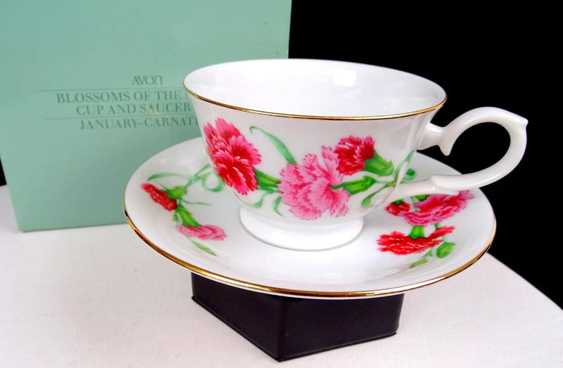 Porcelain teacup and saucer with pink carnation flowers and gold rim, matching handle