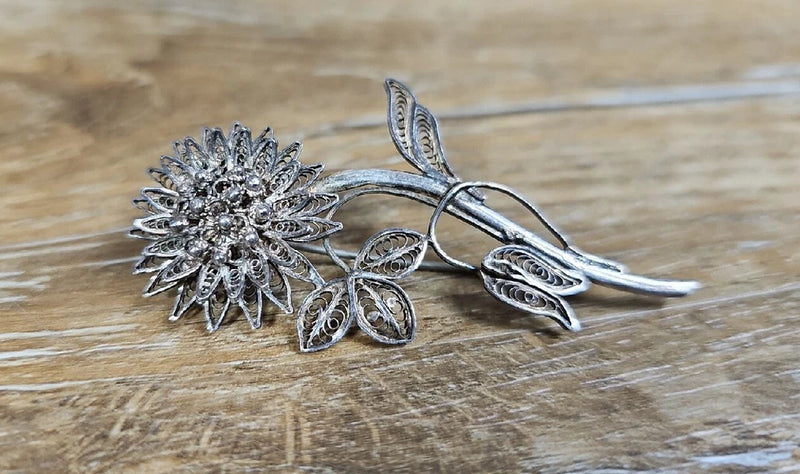 Silver-tone sunflower brooch pin with filigree petals and long stem leaves