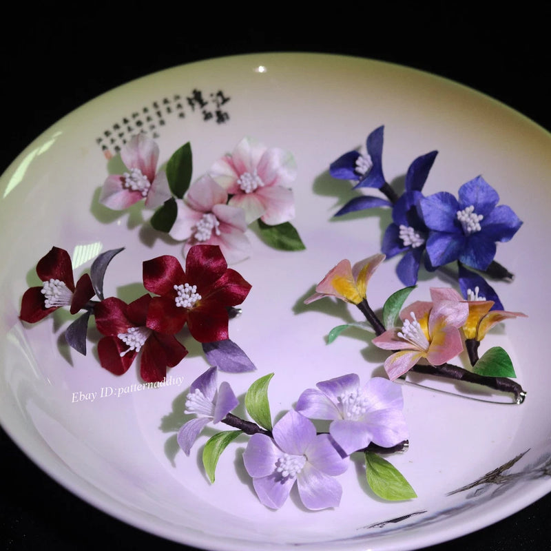 Velvet flower brooches with metal pins, assorted colors and petals on a plate