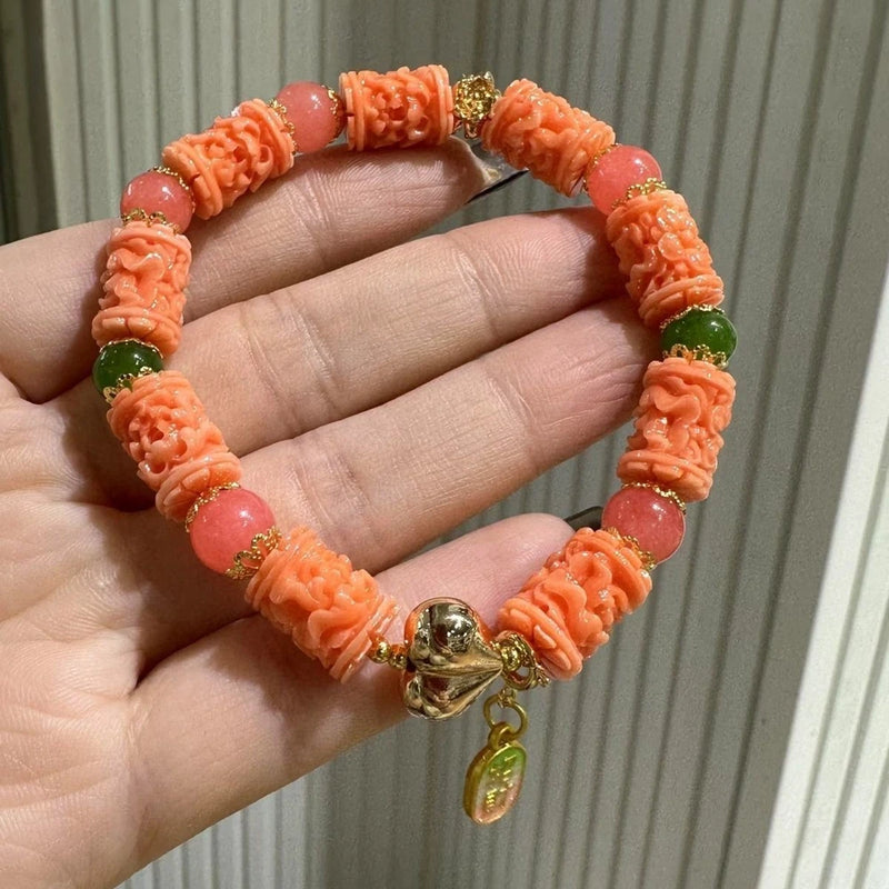 Orange barrel-bead bracelet with peony-style flowers, green beads, gold clasp and charm