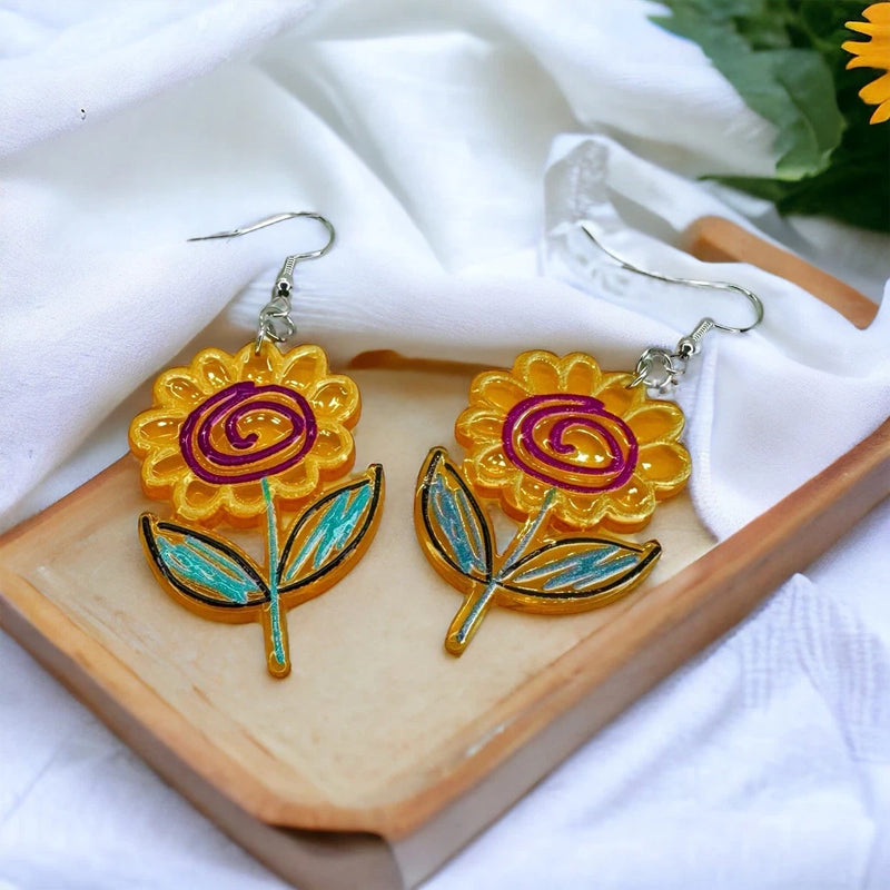 Sunflower dangle earrings with gold petals, purple swirl centers, and blue leaf accents