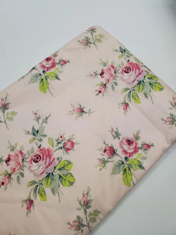 Floral rose quilting fabric with pink and green blossoms on light cream background