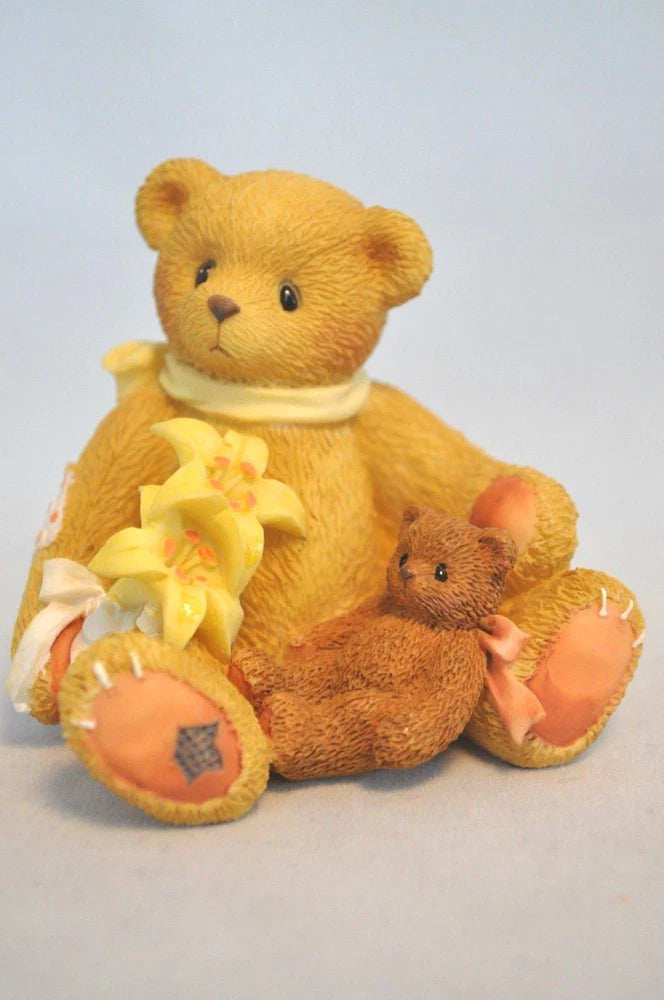 Stuffed teddy bear sitting with a small bear beside it, holding a flower