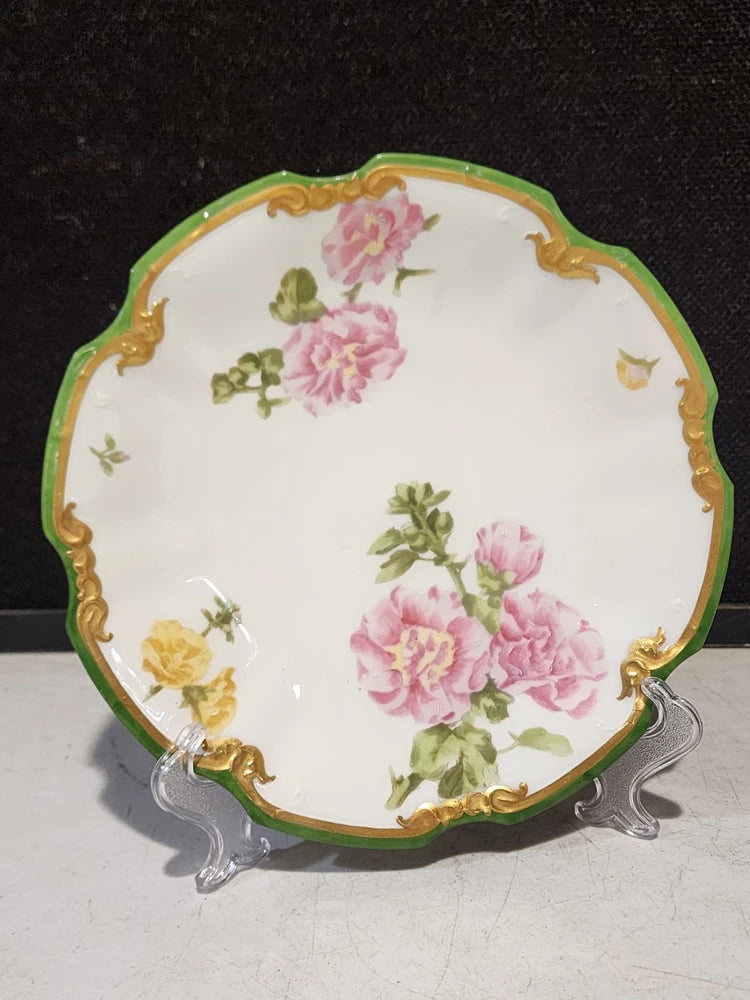 Scalloped floral porcelain plate with green rim, gold trim, pink and yellow carnation design
