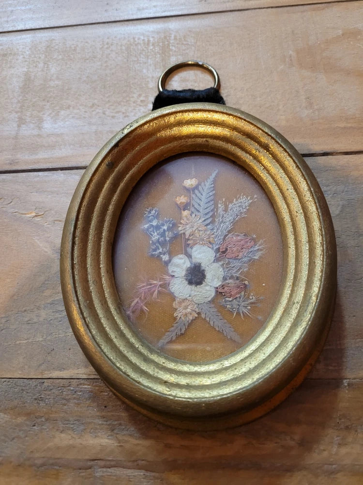 Vintage oval dried flower wall art in gold and brown frame with pressed florals