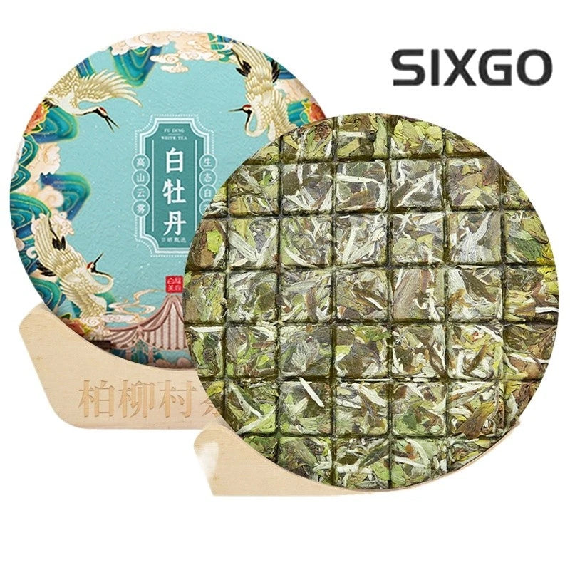 Aged white tea cake, green foil-wrapped tea bricks in a round package
