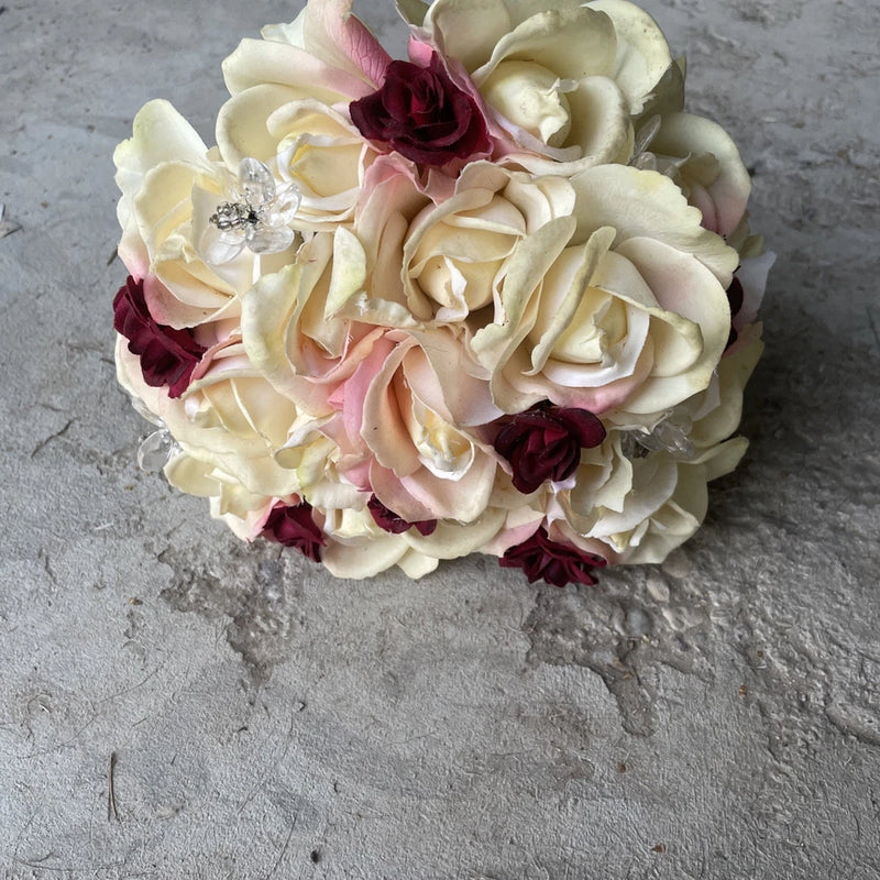 Wedding bouquet with cream, blush, and burgundy roses and a silver embellishment