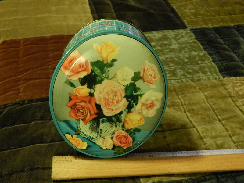Round metal floral gift tin with teal rim and colorful bouquet illustration