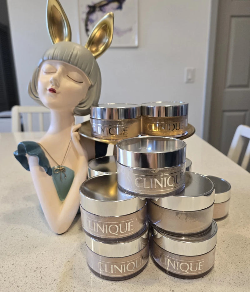 Clinique face powder set in round silver and gold metal tins with logo
