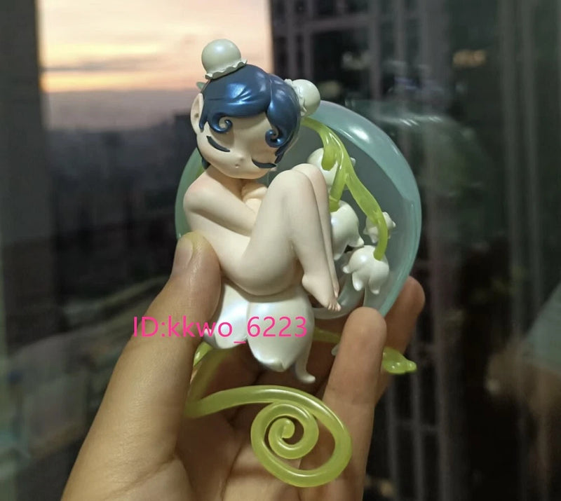 Mint-green elf blind box figure with long leaf-like hair and pale white dress, sitting pose
