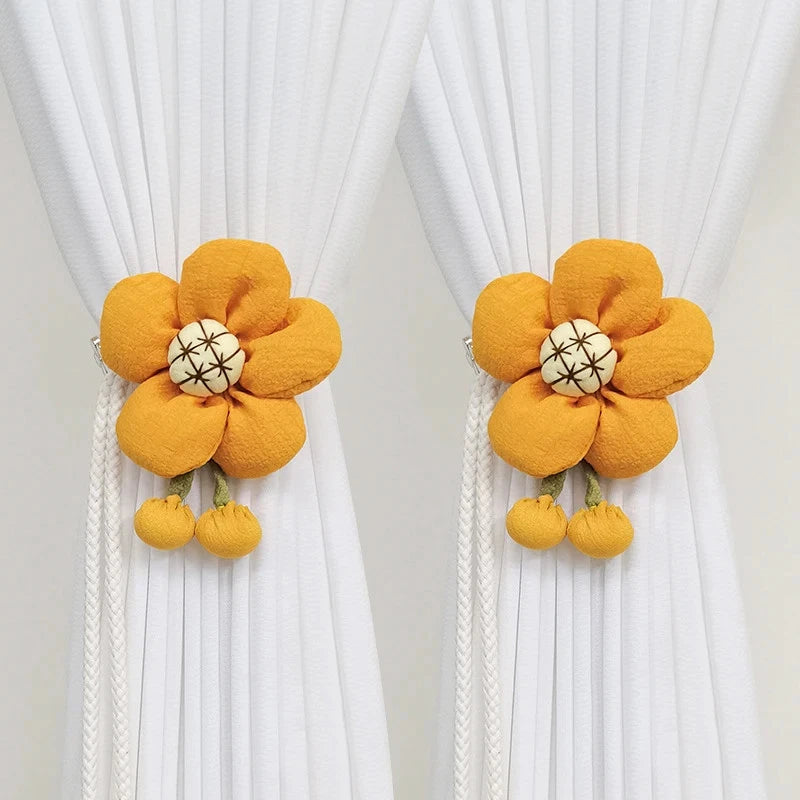 Pair of sunflower fabric curtain tiebacks with yellow flower and white center, pom-pom ends